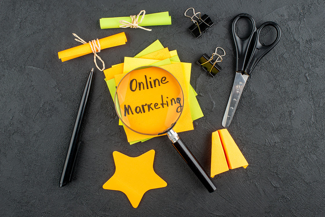 top view online marketing written on sticky notes scroll and star sticky notes scissors binder clips pen lupa on table